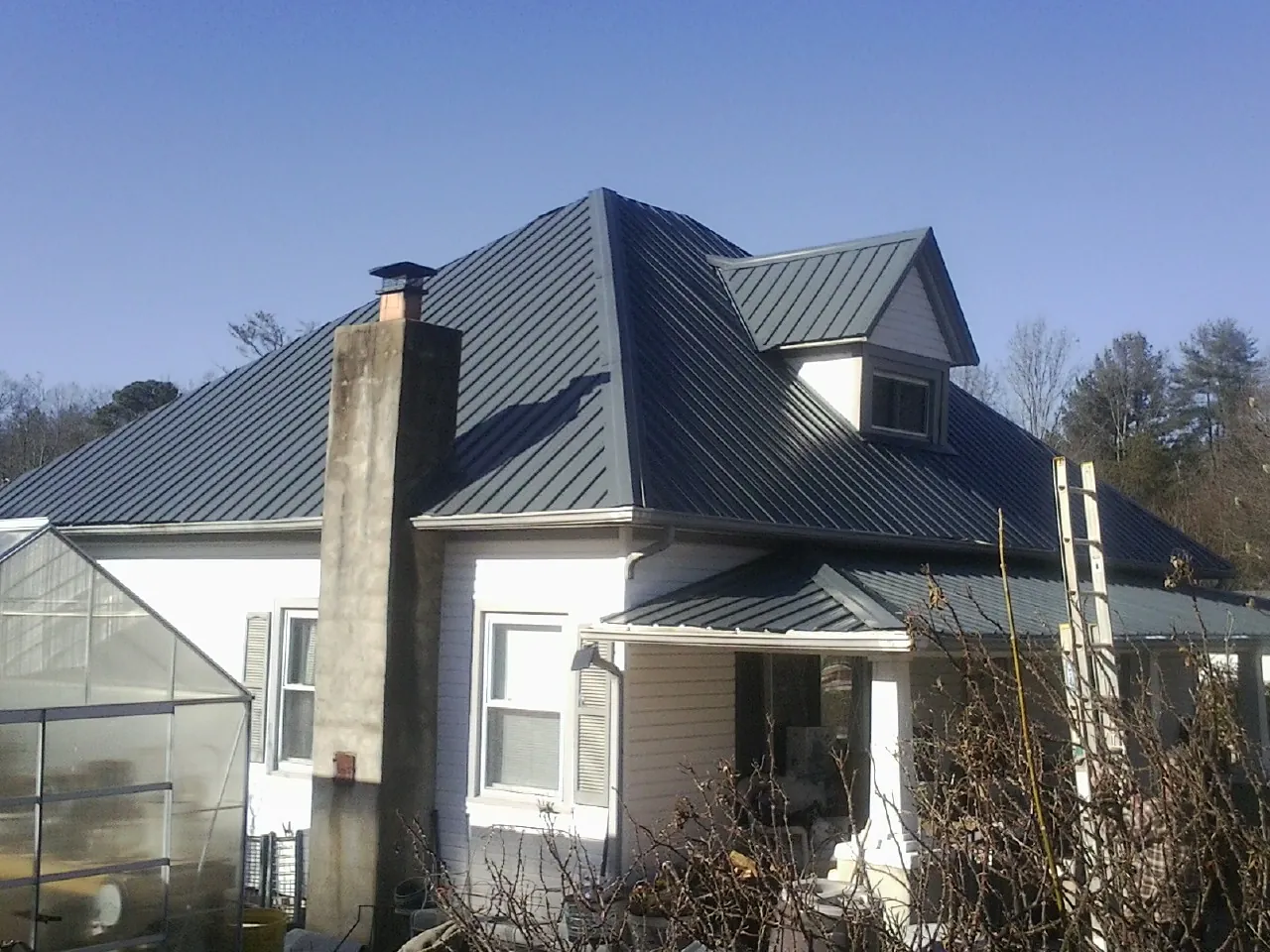 Dark blue standing seam metal roof on a white farmhouse with dormer — Slate & Tile Roof Repair by Roofing Brothers in Pennsauken