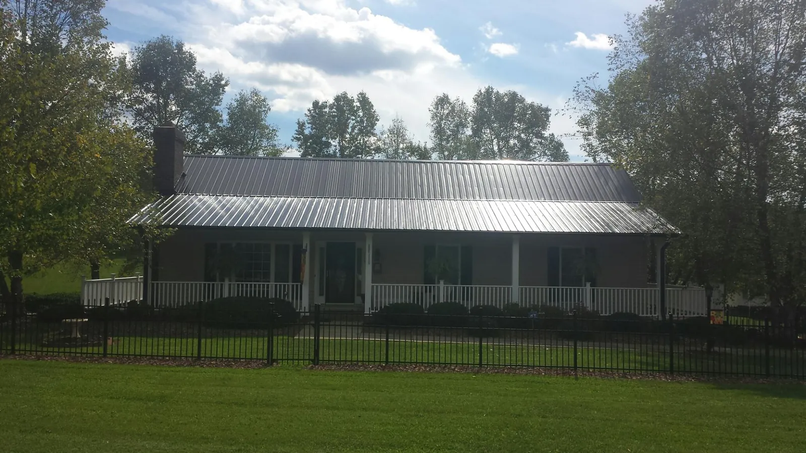 Gray metal roof on a brick ranch with a full width front porch — Gutter Guard Installation work by our crew in Pennsauken