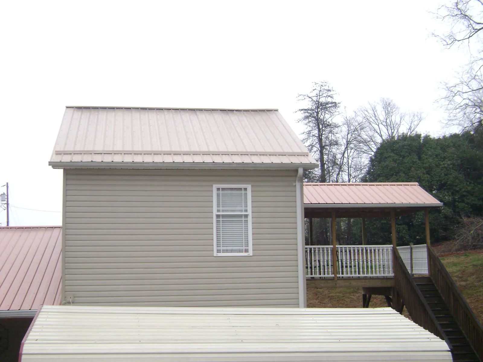 Tan metal roofs on a two story addition and attached porch, from a Roof Replacement job in Pennsauken