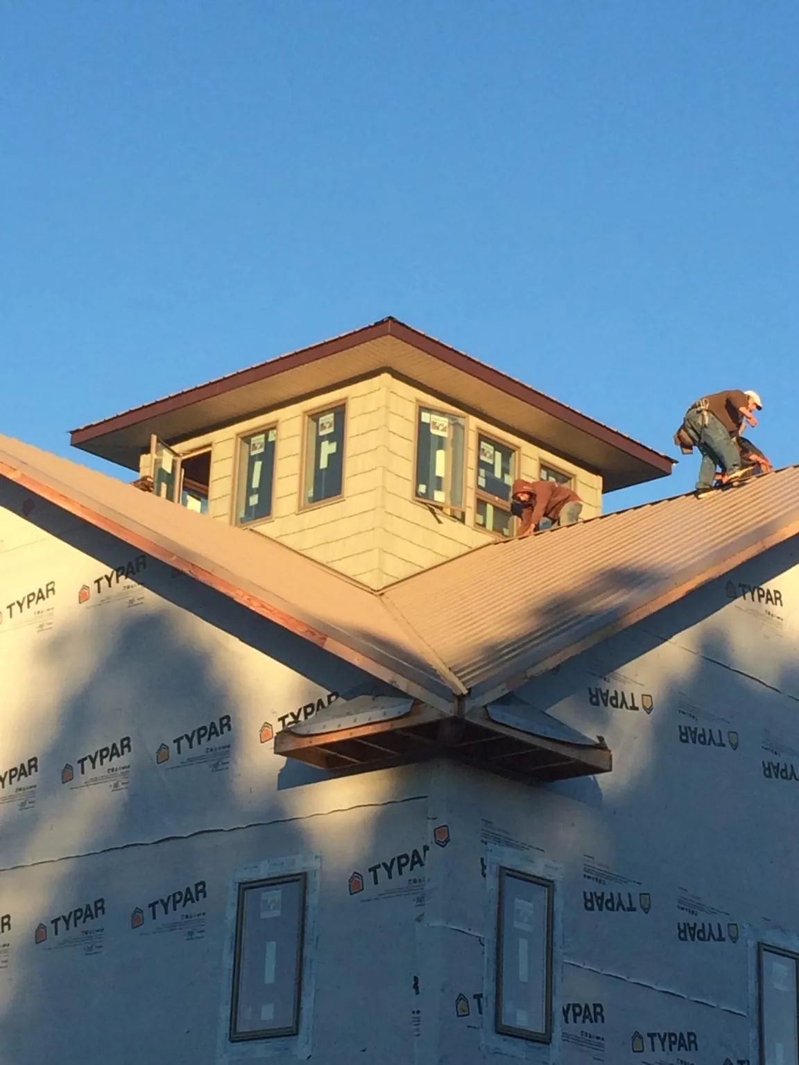 Roofers working around a rooftop cupola on a new metal roof at sunset — Roof Waterproofing in Pennsauken by Roofing Brothers